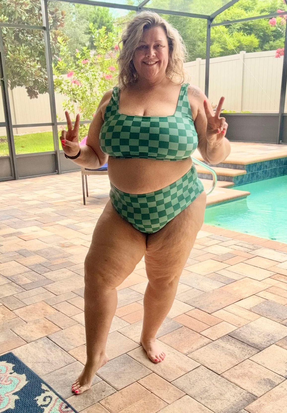 Person wearing a green checkered bikini standing by a pool